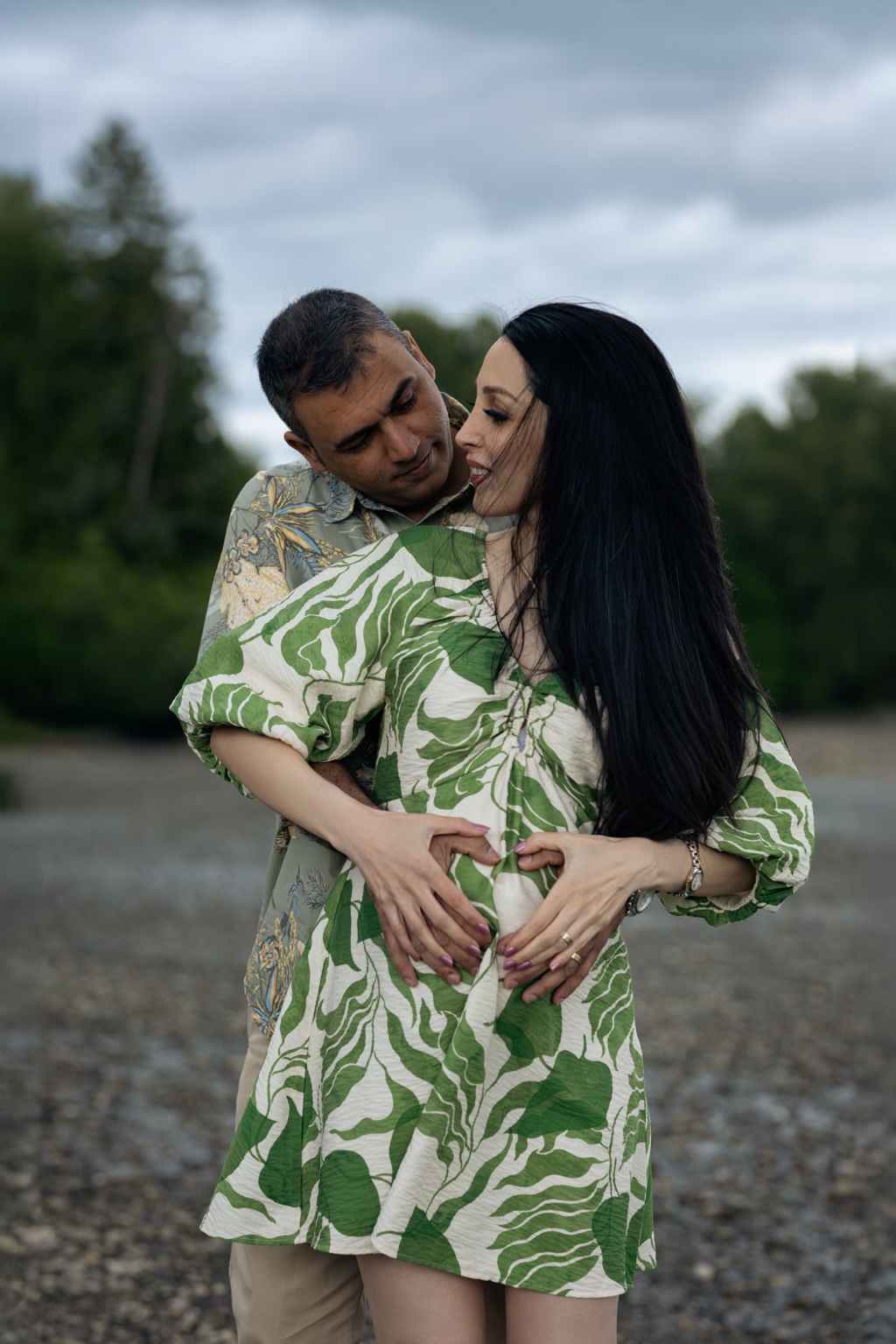 Expecting parents making a heart around the baby bump